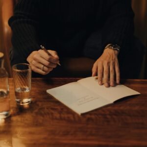 Man signing books during an intimate creative event in a cozy indoor setting.