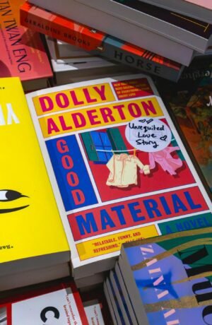 Vibrant mix of books on a shelf, highlighting 'Good Material' by Dolly Alderton.