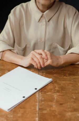 Woman sitting at wooden desk reviewing a screenplay in an office setting.