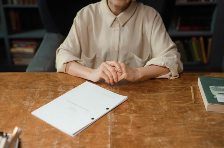 Woman sitting at wooden desk reviewing a screenplay in an office setting.