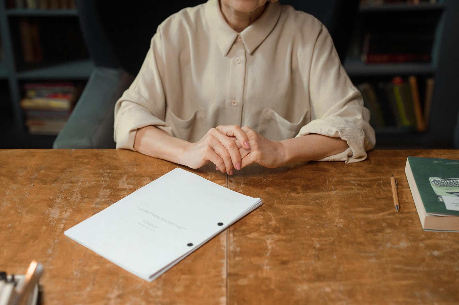 Woman sitting at wooden desk reviewing a screenplay in an office setting.